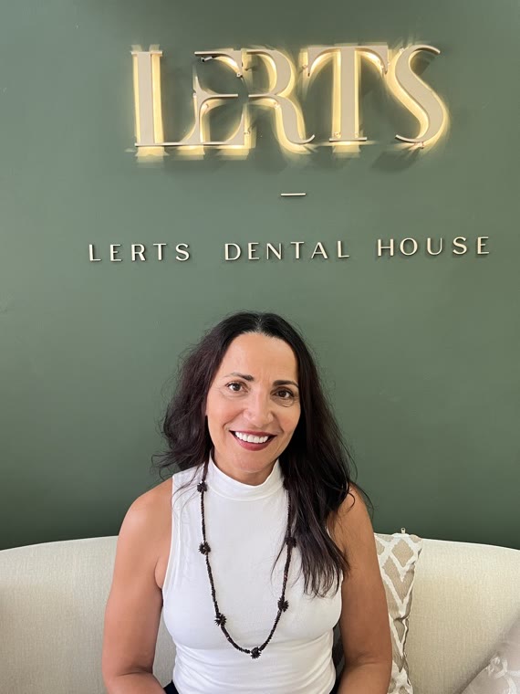 Patient smiling at the LERTS Dental House logo wall, Chiang Mai